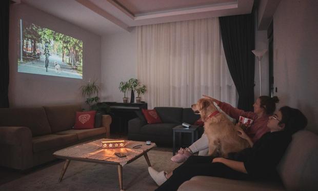 Una familia ve la televisión junto a su perro. (mgstudyo)