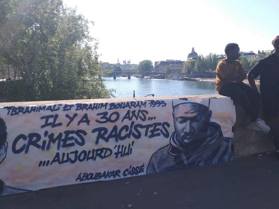 Banderole qui montre un portrait d'Aboubakar Cissé, tué en avril à Poissy. Slogan : "Ibrahim Ali et Brahim Bouarram 1995. Il y a 30 ans... CRIMES RACISTES ...Aujourd'hui. Aboubaka Cissé". Deux hommes
