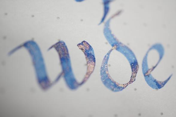 "wde" in periwinkle ink with gold glitter, written in Carolingian minuscule