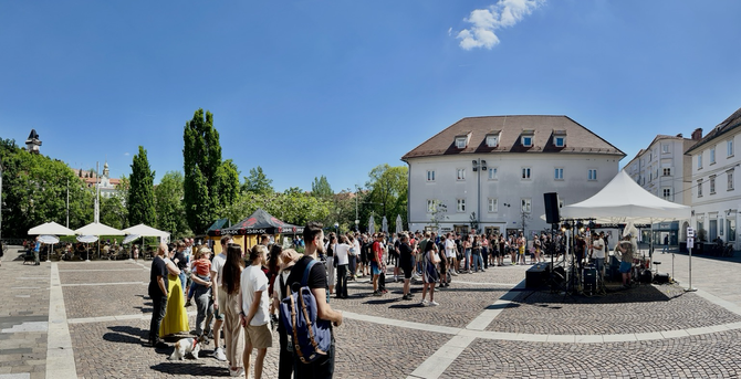Städtischer Platz mit vielen Personen vor einer Bühne mit der Band rote Knaben