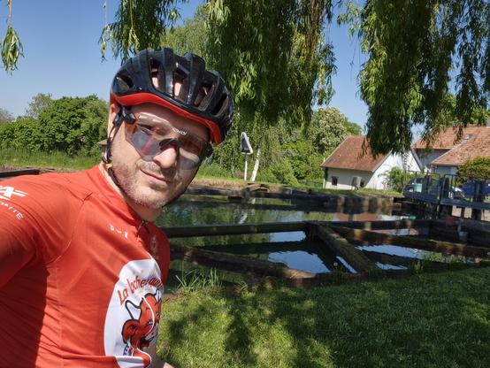 Selfie en tenue de cycliste devant une écluse, et sous un saule pleureur.