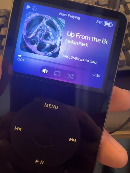 Imagem de um dispositivo eletrônico para reprodução de músicas com uma tela. Na tela mostra a música atual.