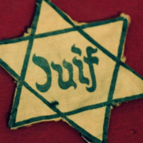 Yellow cloth Star of David of the type Nazis forced Jews to wear, containing the word “Juif”, the French word for “Jew”.