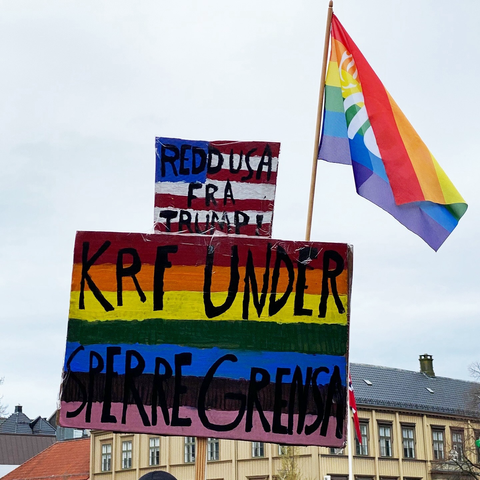 A rainbow sign that says "KrF under sperregrensa" (a Christian party in Norway has attempted culture war and is wished poor electoral outcomes) and "save the US from Trump".