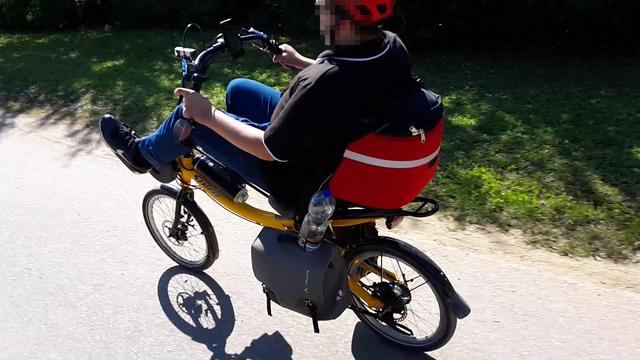 Jemand radelt auf einem gelben Sesselrad.