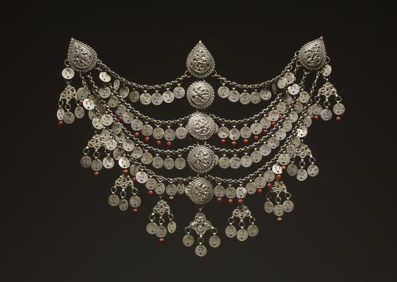 From the Republic of North Macedonia (Mijak tribal area), a woman's head-ornament (igla) dated 20thC. 

Created from copper alloy with silver, the igla has four chains linked by five central stamped ornaments. The three upper chains are hung with small circular pierced discs, the bottom chain hung with amulets in the form of a cast element with three suspended discs. 

Red beads hang from the discs on the second and fourth rows. The chains end in hooks which can be attached to a headscarf at top and sides so that the amulets hang over the forehead. 

At the centre point, the igla measures : height 22.30cm, length 22cm, width: 30cm 

Source : British Museum,  Aquision Number : Eu1997,04.150 

#BeadSocietyGB #Beads #HistoryOfBeads #BritishMuseum #Igla #MijakTribalArea