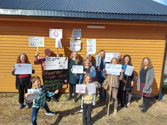 A small crowd of working class people of all ages, carrying protest signs in support of working class causes. Workers unions, workers cooperatives, international solidarity, quality in public education, 2 day work week + 5 day weekend, and others
