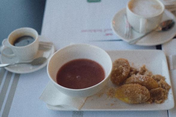 The semolina flammery with the red strawberry sauce in a white bowl next to it.