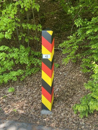 Eine Grenzsäule mit der Nummer 42  in den Farben schwarz-rot-gold im Wald. Gefunden am Neißeradweg bei Zittau.