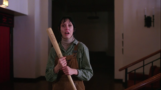 A woman holding a baseball bat and looking terrified