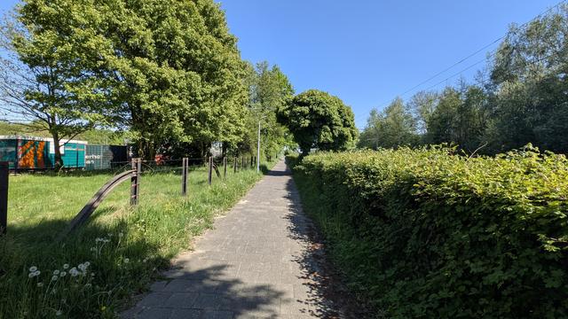 Der "Borgerfietspad": Ein schmaler und schlecht gepflasteter Gehweg, zwar von etwas Grün umsäumt, aber unmittelbar an Bahn/Autobahn gelegen.