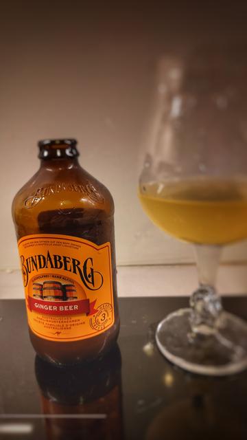 Une bouteille 33cl de GingerBeer en canette de verre old school Bundaberg et un verrecà bière à coté à moitier plein.