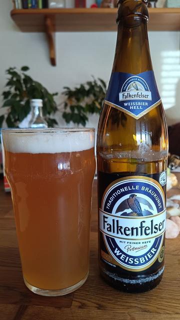 Auf einem Tisch steht ein mit Bier gefülltes Glas und daneben die dazugehörige Flasche mit Aufschrift: Falkenfelser Weissbier