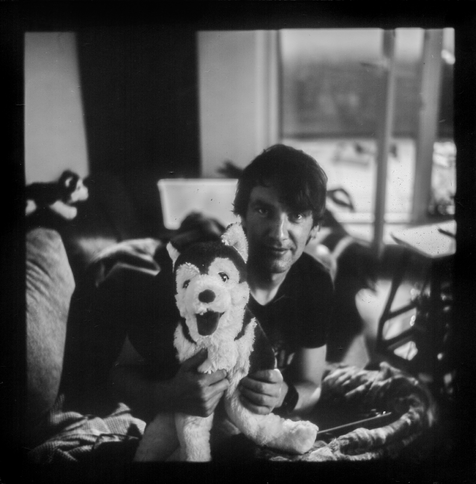 Black and white image of pandora with a plush husky, this image was flipped along the horizontal axis and colors inverted and edited since the original is the flipped and negative version