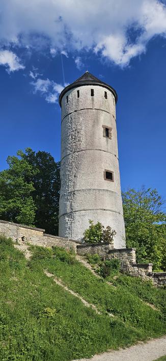 Burgturm. Dahinter blauer Himmel und Wolken.