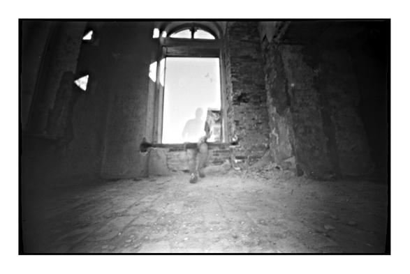 Blurred black and white portrait of a man against the background of an abandoned house window. Shot on film and pinhole camera