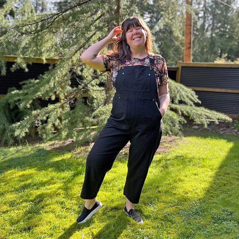 Helen wears black overalls with silver hardware and a printed tee.