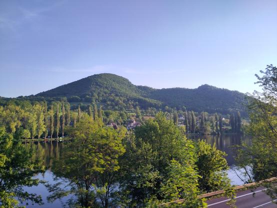 two hills at the background and a river with trees on sides in the foreground