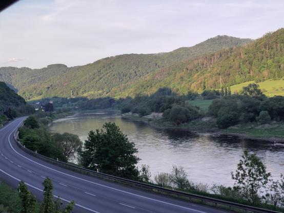 river turn with a road turning around and forest mountains at the back
