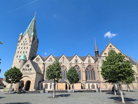 Große Kirche vor blauem Himmel. Im Vordergrund ein paar Bäume.