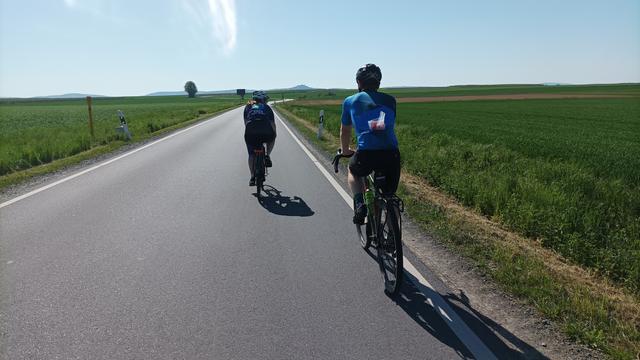 Zwei Radfahrer auf der Landstrasse von hinten photographiert, am Horiznt der Otzberg.