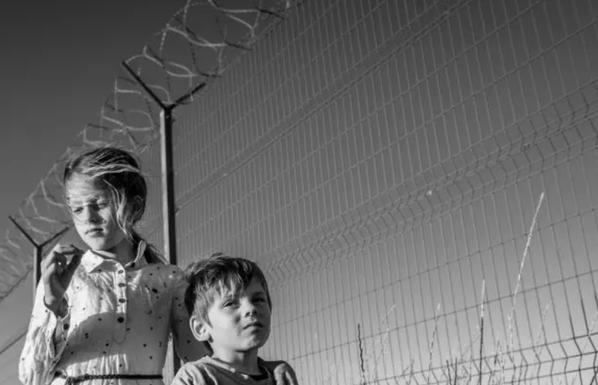 2 enfants devant des barbellés