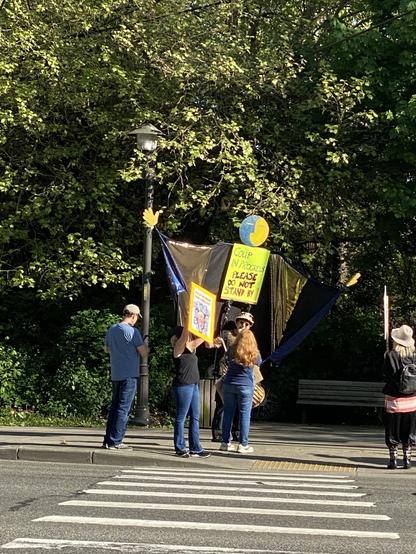 a giant puppet in ukrainian colours (mostly) on the far side of the street with less protest space