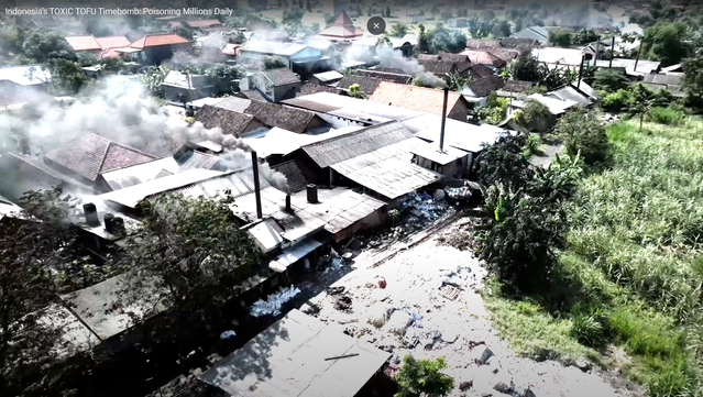 an aerial shot of a village in indonesia with black smoke billowing everywhere from cooking fires from industrial tofu production using plastic waste as fuel