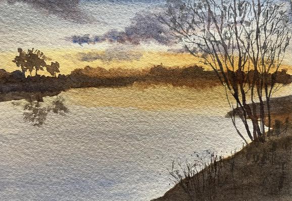 A quiet river stretches across the scene, reflecting a cluster of trees on the left and bare branches on the right, with soft, textured clouds drifting above a distant, low horizon.