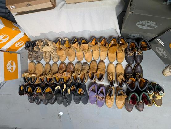 My collection of 22 pairs of Timberland boots are arranged in 3 rows on the floor, overhead view.