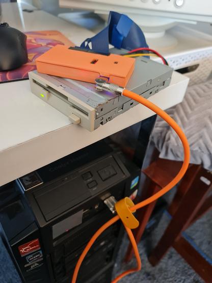 photo of a Greaseweazle v4.1 in a 3d printed enclosure, connected to a floppy drive and then to PC via USB