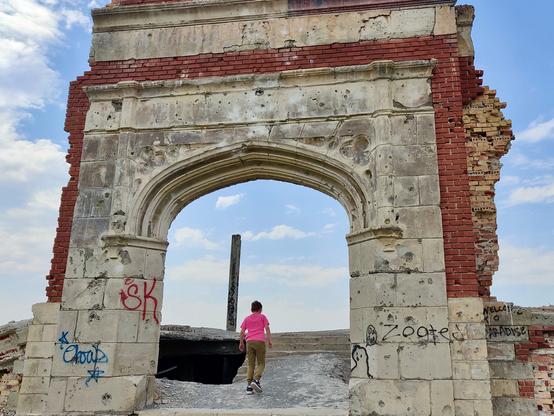 A young boy ascends the steps through the archway of the old school building.