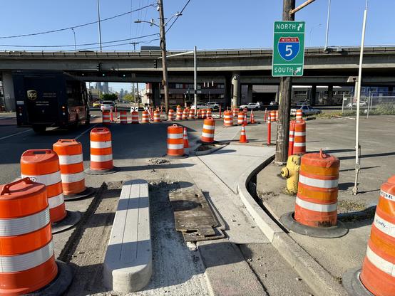 Construction area where a concrete curb protected bike lane will curve to the right up to sidewalk level before crossing Spokane Street