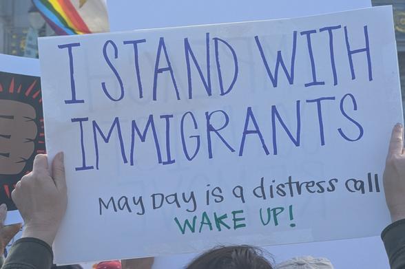 Sign reading "I stand with immigrants. May Day is a distress call. Wake up!"
