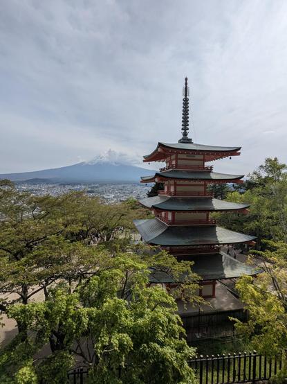 Die berühmte Pagode von Kawaguchiko zwischen grünen Bäumen und dem Vulkan Fuji im Hintergrund.
