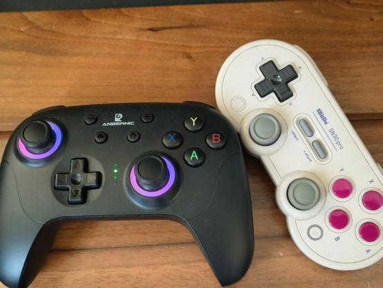 A picture of an Anbernic RG P01 next to a 8Bitdo SN30 Pro