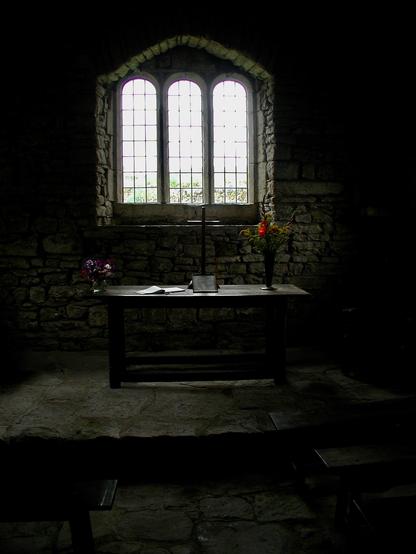 The interior of Keld Chapel, Cumbria, a sark interior lit by the window above the alter.