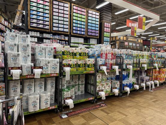 A big box hardware store. There are shelves full of different brands of toilet paper, and each shelf has a toilet paper roll with toilet paper in it for you to feel the quality of