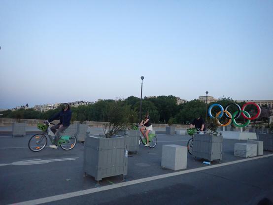 Trois cyclistes devant les anneaux Olympiques du pont d'Iéna