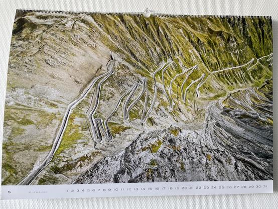 The beautifully winding road of Passo Stelvio / Stilfserjoch on a sunny day. An awesome collection of hairpin curves photographed from above, so it looks like they were stacked upon each other.