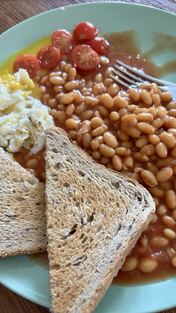 Picture of an english breakfast: beans and toast with a (messed-up) sunny-side egg and roasted tomatoes