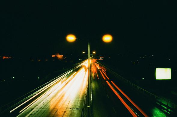 A long exposure night photo of a straight road from above with headlights and taillights trails
