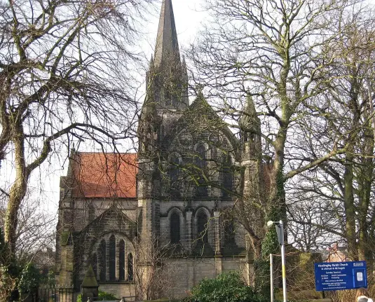 The image depicts a church building, notable for its tall spire and architectural features typical of Gothic Revival style. The structure is surrounded by trees that appear to be bare, suggesting it may be during a cooler season. There is also a sign in front of the church, likely providing information about the location or services offered. The overall ambiance suggests a serene and historic setting.

Image Credits: Wikimedia / Chemical Engineer / CC BY-SA 3.0