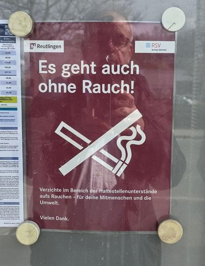 In einem Fahrplanaushang an einer Bushaltestelle in Reutlingen hängt ein Plakat, dass darum bittet, im Bereich der Unterstände nicht zu rauchen.