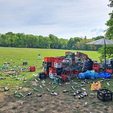 Mehr als 30 Bierkästen sind zu einem Haufen übereinander gestalpelt. Drum herum erstreckt sich ein Teppich aus leeren Flaschen mitten im Park