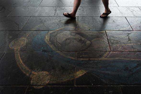 A chalk drawing of Mary on the pavement in a street in Melbourne, Australia. The legs of a person walking on top of it can be seen