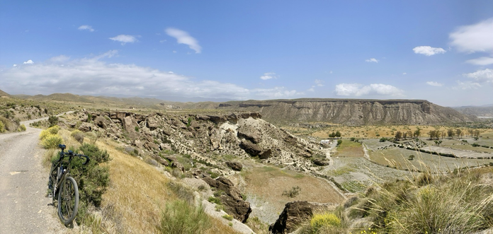Blick in eine angegrünte aride Landschaft mit Canyon. Links ein Rad.