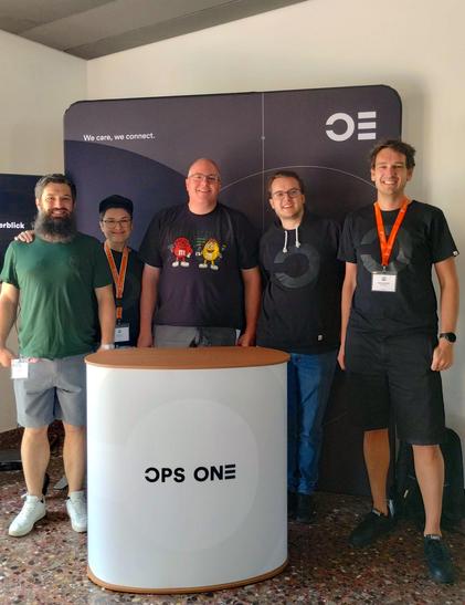 Ein Gruppenbild von Andri, Sereina, Mario, David und Martin vor dem Ops-One-Messestand.