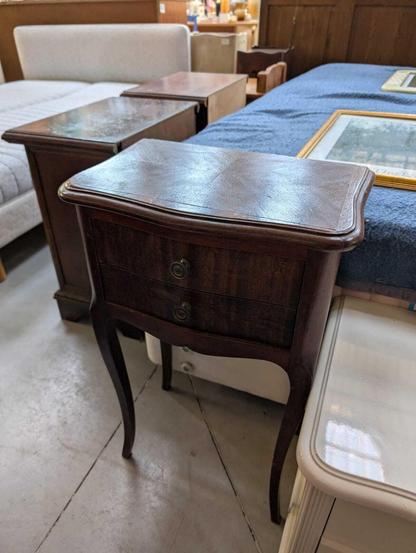 a wooden bedside table with slim shapely legs and two small draws with little round knobs. It is quite simple but looks beautiful and well made.