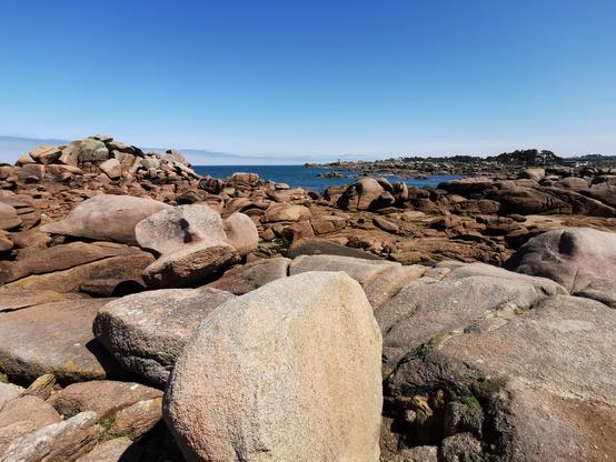 Un paysage côtier avec de nombreux rochers. On aperçoit la mer au fond.